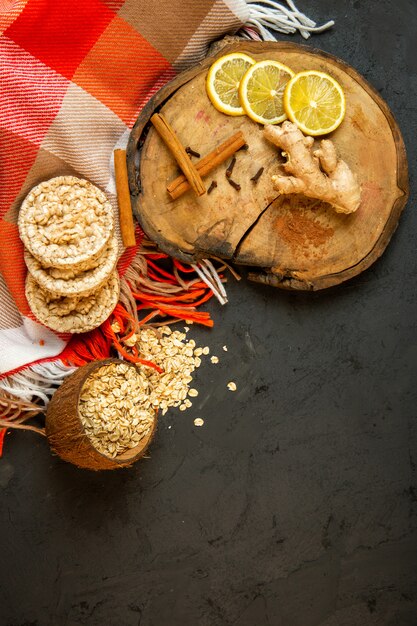 Draufsicht der Zusammensetzung mit Mais-Diätbrot mit Zimtstangen-Zitronenscheiben und Ingwer auf Schwarz