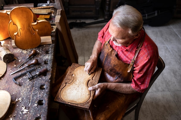 Draufsicht des älteren Zimmermanns, der in seiner altmodischen Werkstatt arbeitet