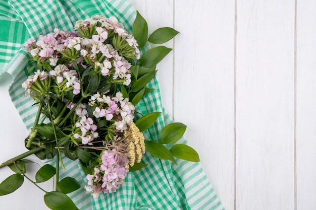 Draufsicht des Blumenstraußes auf einem grünen karierten Handtuch auf einer weißen Oberfläche