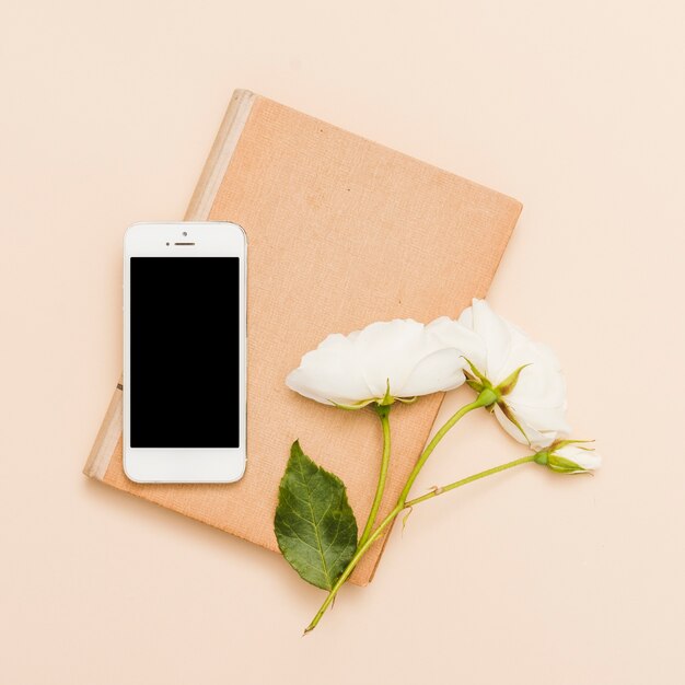 Draufsicht des Buches, des Smartphone und der Blumen