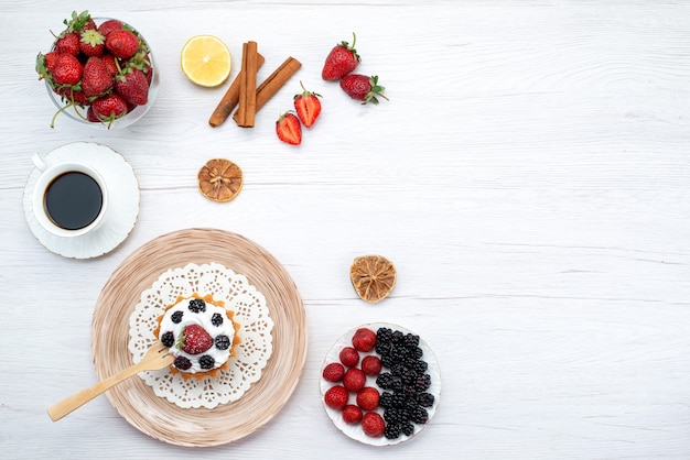 Draufsicht des cremigen Kuchens mit Beeren zusammen mit Zimtkaffeekirschen auf hellem Schreibtisch, Kuchen süß