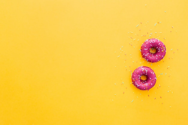 Draufsicht des Donuts in der rosa Zuckerglasur auf gelbem Hintergrund