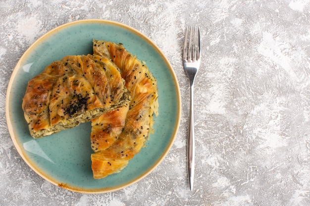 Draufsicht des Gebäcks mit der köstlichen Teigmahlzeit des Fleischs innerhalb der Platte, die auf heller Oberfläche geschnitten wird