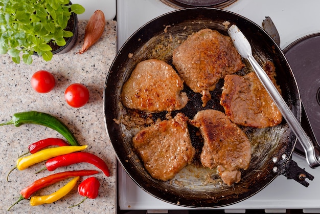 Draufsicht des gebratenen Schweinesteaks auf der rustikalen Pfanne