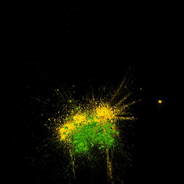 Draufsicht des gelben und grünen holi farbigen Pulvers über schwarzem Hintergrund