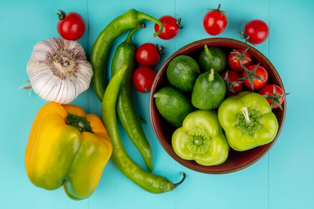 Draufsicht des Gemüses als Gurkenpfeffertomate in Schüssel und Knoblauch auf blauer Oberfläche