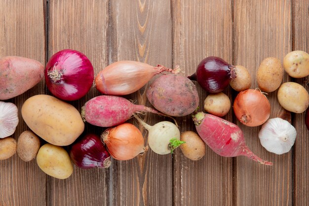 Draufsicht des Gemüses als Kartoffelrettichzwiebelknoblauch auf hölzernem Hintergrund