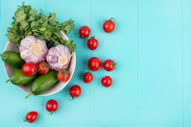 Draufsicht des Gemüses als Tomatengurkenkoriander und Knoblauch in der Schüssel auf blauer Oberfläche