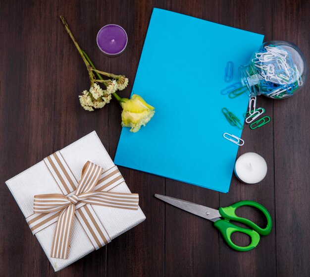 Draufsicht des Geschenks mit Bogenband mit gelber Rose auf einer Holzoberfläche mit Kopienraum