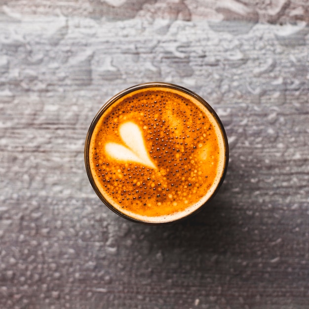 Draufsicht des geschmackvollen kaffeeglases mit lattekunst auf wassertropfenhintergrund