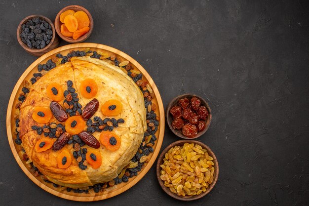 Draufsicht des geschmackvollen Shakh Plov gekochten Reises innerhalb des runden Teigs mit Rosinen auf grauer Oberfläche