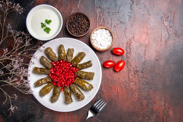 Draufsicht des grünen Blattdolmas mit Granatäpfeln auf dunkler Oberfläche