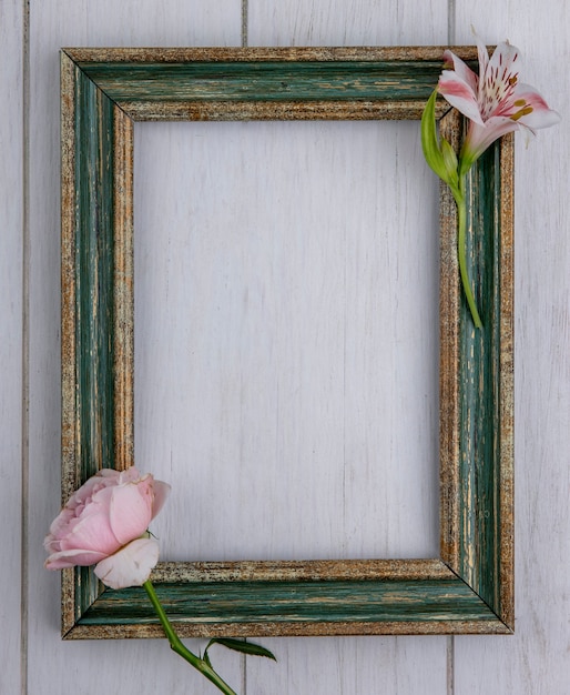 Kostenloses Foto draufsicht des grünlich-goldenen rahmens mit hellrosa rose und lilie auf einer grauen oberfläche
