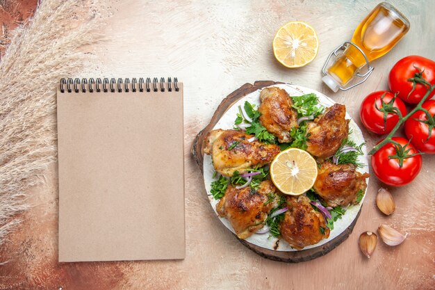 Draufsicht des Hühneröl-Tomaten-Knoblauch-Zitronen-Huhns mit Kräutercreme-Notizbuch