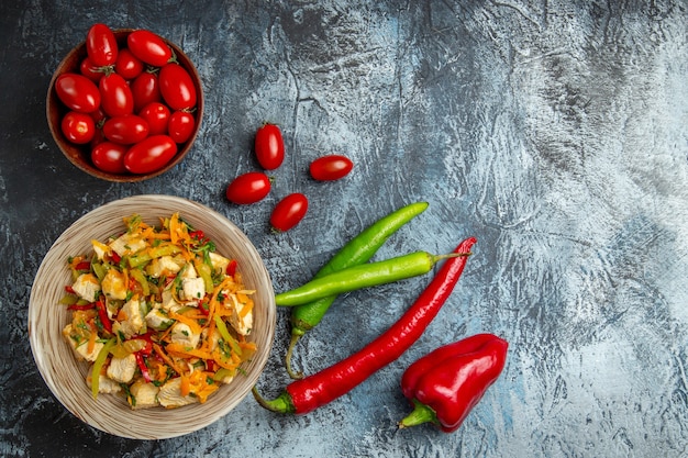 Draufsicht des Hühnersalats mit roten Tomaten auf heller Oberfläche