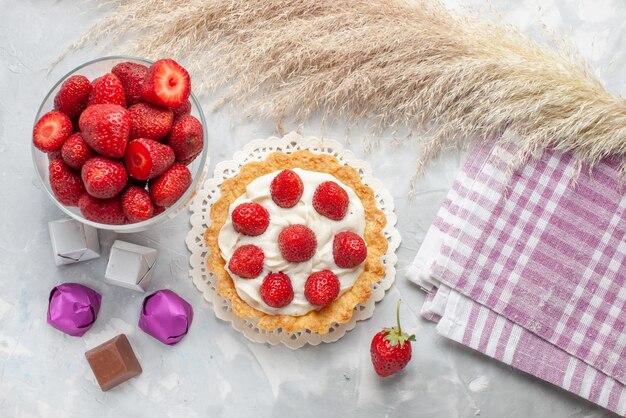 Draufsicht des kleinen Kuchens mit Sahne und frischer roter Erdbeeren rosa Sahnekuchen auf Weißlichtschreibtisch, Kuchenfrucht-Beeren-Kekscreme