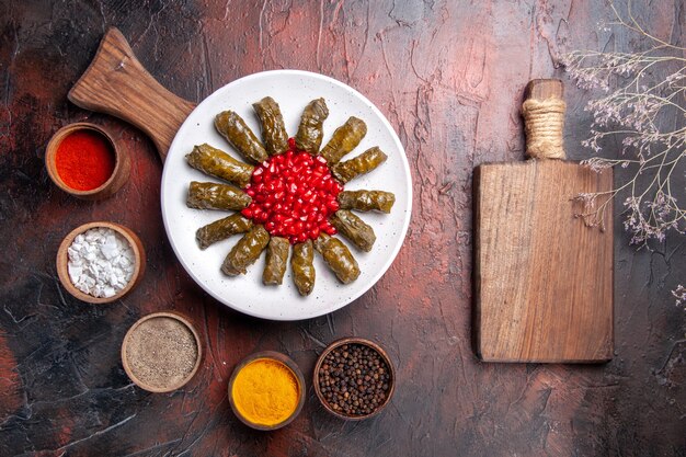 Draufsicht des köstlichen Blattdolmas mit Gewürzen auf dunkler Oberfläche