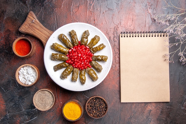 Draufsicht des köstlichen Blattdolmas mit Gewürzen auf dunkler Oberfläche