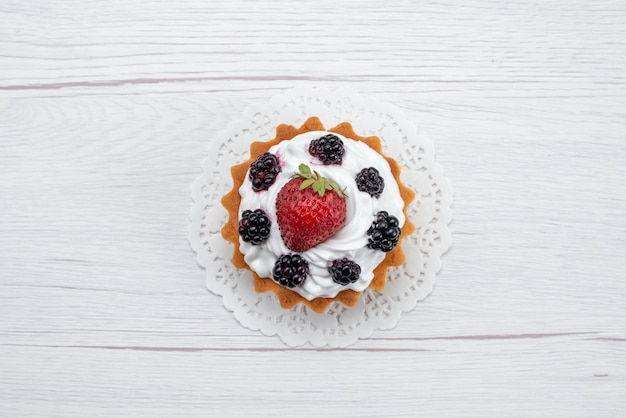 Draufsicht des köstlichen kleinen Kuchens mit Sahne und Beeren auf Weiß, Kuchenkeks backen Frucht süß