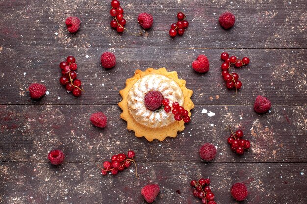 Draufsicht des köstlichen kleinen Kuchens mit Zuckerpulver zusammen mit Himbeeren-Preiselbeeren entlang des braunen Beerenfruchtkuchen-Kekses