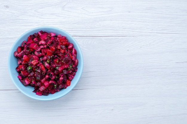 Draufsicht des köstlichen Rübensalats, der mit Gemüse und Gemüse in blauer Platte auf leichtem, pflanzlichem Vitamin-Lebensmittelmahlzeit-Gesundheitssalat geschnitten wird