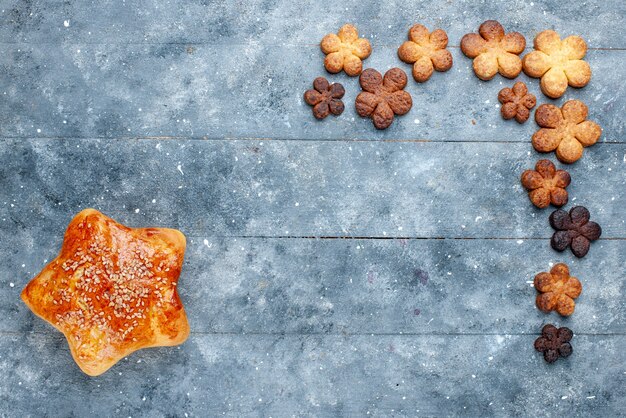 Draufsicht des köstlichen süßen Gebäcksterns geformt mit Plätzchen auf grauem Schreibtisch, süßes Backgebäckkuchen