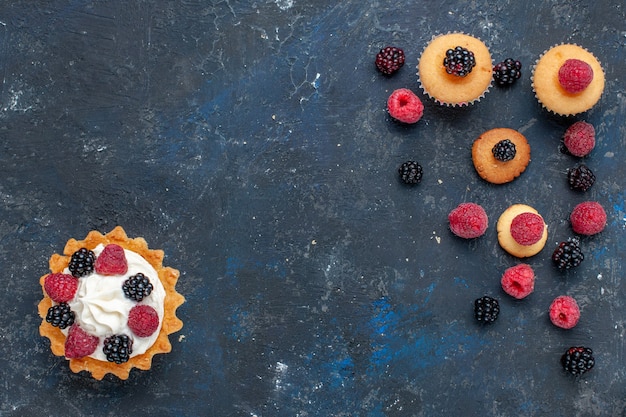 Draufsicht des köstlichen süßen kuchens mit verschiedenen beeren und der leckeren sahne auf dunklem, fruchtigem beerenkuchen-keks süß