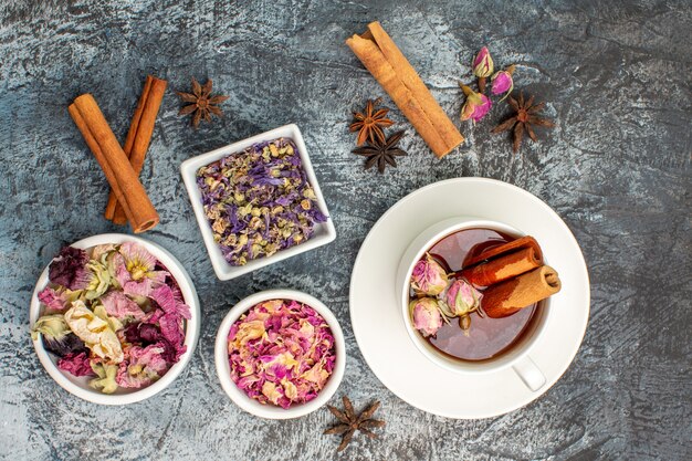 Draufsicht des Kräutertees mit trockenen Blumen und Anis und Zimt auf grauem Hintergrund