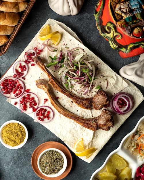 Draufsicht des Lammrippen-Kebabs mit Kräuterzwiebeln und Granatapfelbohnen auf Lavash