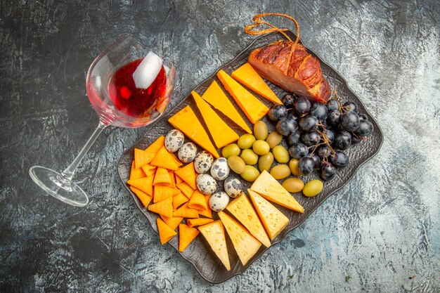 Draufsicht des leckeren besten Snacks auf einem braunen Tablett und gefallenem Weinglas auf Eishintergrund