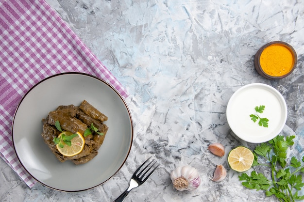 Draufsicht des leckeren Blattdolmas mit Knoblauch und Joghurt auf weißer Oberfläche