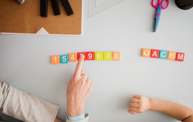 Draufsicht des Lehrers, der Kind am Schreibtisch über Zahlen und Buchstaben unterrichtet