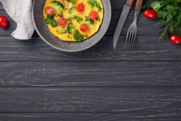 Draufsicht des Omeletts zum Frühstück mit Tomaten und Tischbesteck
