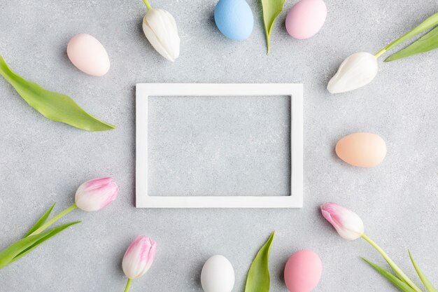 Draufsicht des Rahmens mit bunten Ostereiern und Tulpen