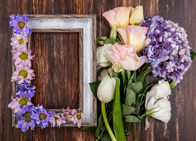 Draufsicht des Rahmens und der Blumen darauf und auf hölzernem Hintergrund mit Kopienraum