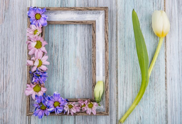 Draufsicht des Rahmens und der Blumen darauf und auf hölzernem Hintergrund mit Kopienraum