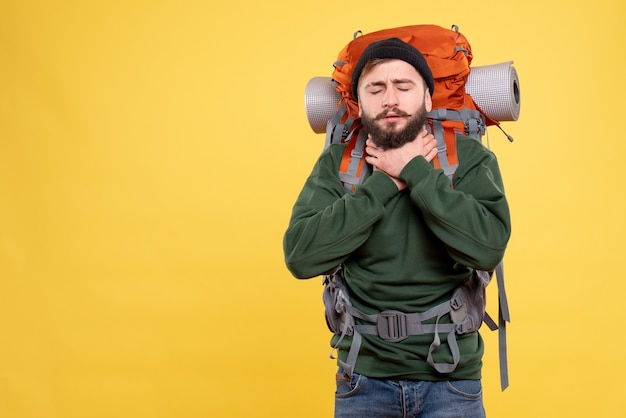 Draufsicht des Reisekonzepts mit dem unruhigen jungen Mann mit Packpack, der unter Halsschmerzen leidet