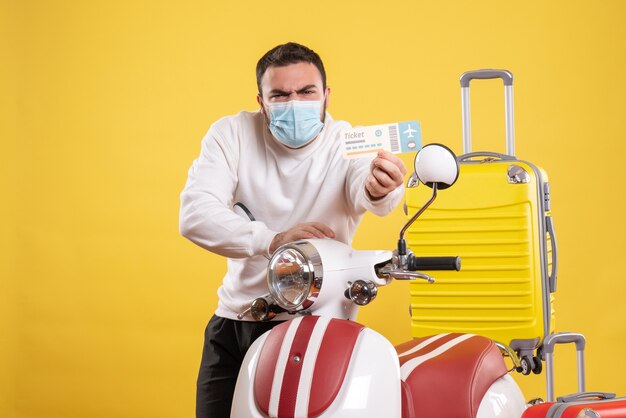 Draufsicht des Reisekonzepts mit jungem Mann in medizinischer Maske, der in der Nähe des Motorrads steht