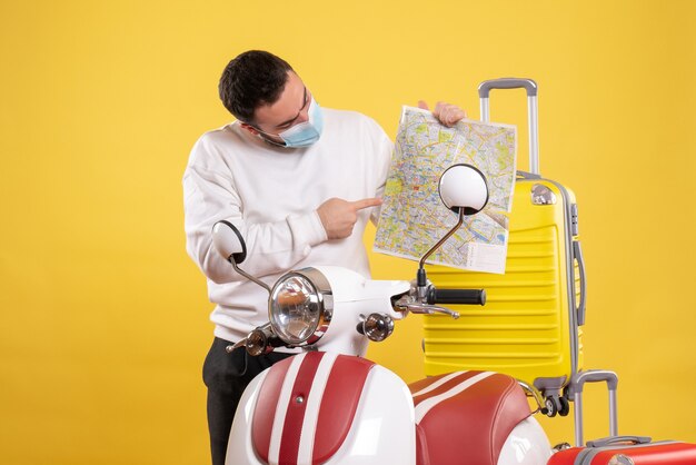 Draufsicht des Reisekonzepts mit jungem Mann in medizinischer Maske, der in der Nähe des Motorrads steht