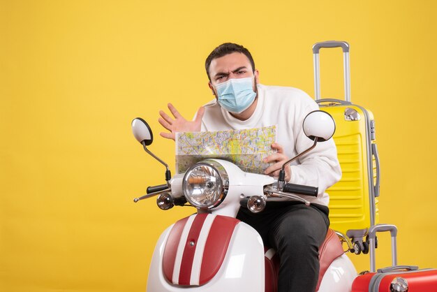 Draufsicht des Reisekonzepts mit verwirrtem Kerl in medizinischer Maske, der auf einem Motorrad mit gelbem Koffer darauf sitzt und Karte hält