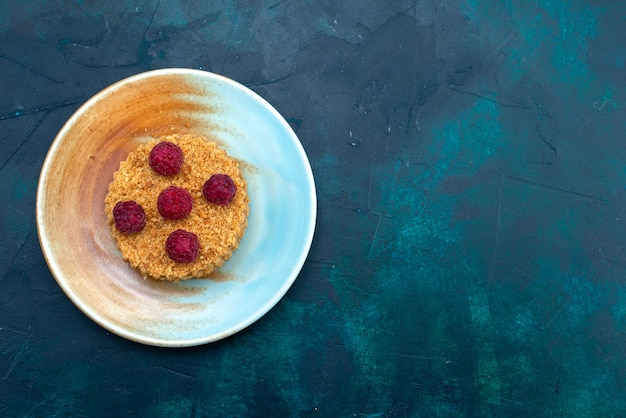 Draufsicht des runden kuchens mit frischen himbeeren innerhalb platte auf der dunkelblauen oberfläche