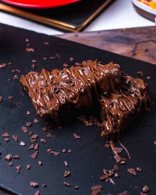 Draufsicht des Schokoladenkuchens mit Schokoladencreme auf schwarzer Oberfläche