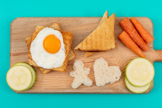 Draufsicht des Spiegeleis mit Toast und Gemüse auf der blauen Oberfläche horizontal