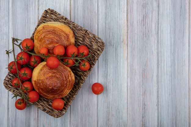 Draufsicht des traditionellen aserbaidschanischen Gebäckgogals auf einem Weidentablett mit Weinreben-Tomaten auf einem grauen hölzernen Hintergrund mit Kopienraum