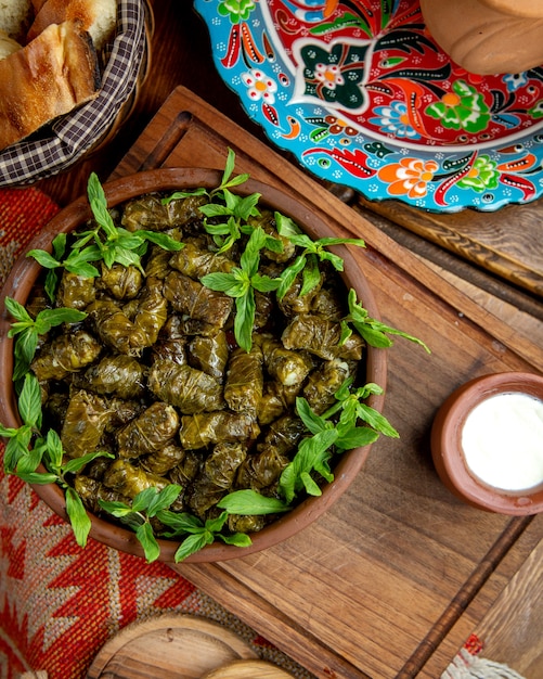 Draufsicht des traditionellen Dolmas in den Weinblättern mit saurem Joghurt auf einem Holztisch