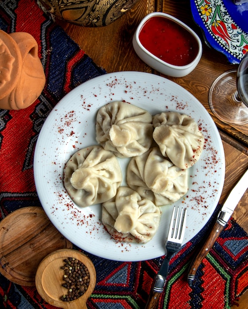 Draufsicht des traditionellen georgischen Khinkali mit Sumakh und der würzigen Soße auf einem weißen Teller