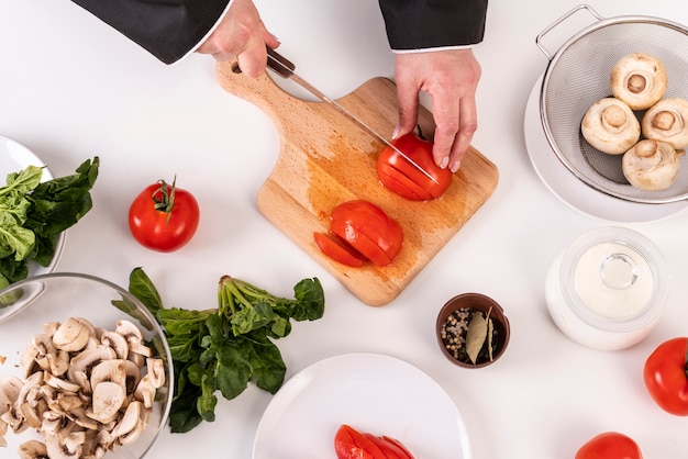 Draufsicht des weiblichen Kochs, der Tomaten schneidet