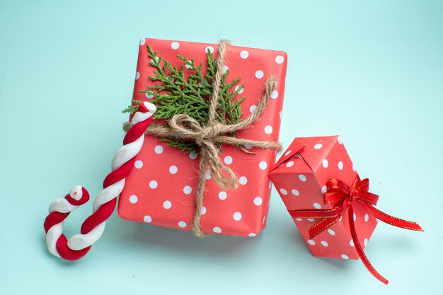 Draufsicht des Weihnachtshintergrundes mit roten Geschenkboxen und Süßigkeiten auf pastellgrünem Hintergrund