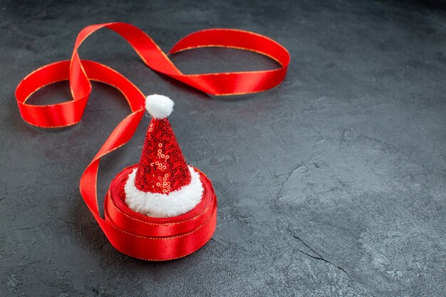 Draufsicht des Weihnachtsmannhutes auf einer Rolle des Bandes auf der rechten Seite auf dunklem Hintergrund