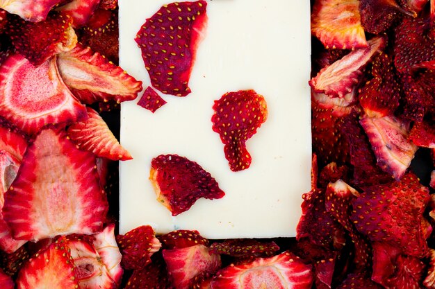 Draufsicht des weißen Schokoladenriegels auf getrocknetem Erdbeerscheibenhintergrund